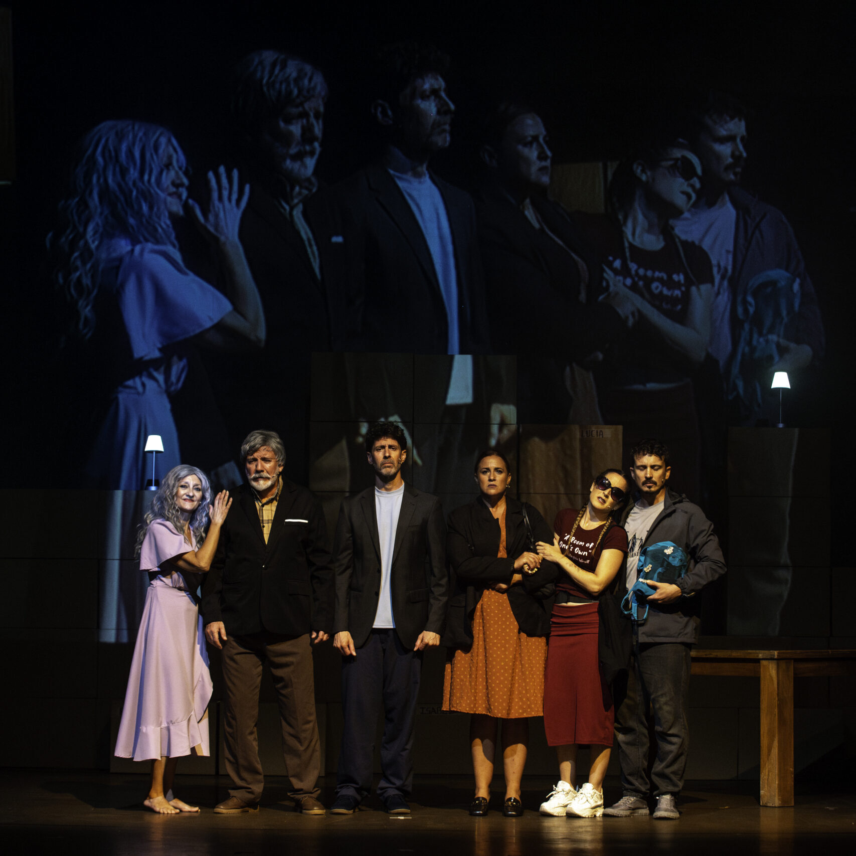 Actores en obra teatral con proyección de fondo