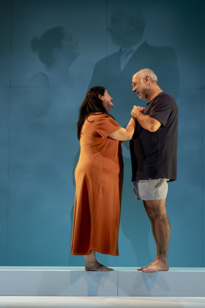 Pareja en escenario azul, abrazándose y sonriendo.