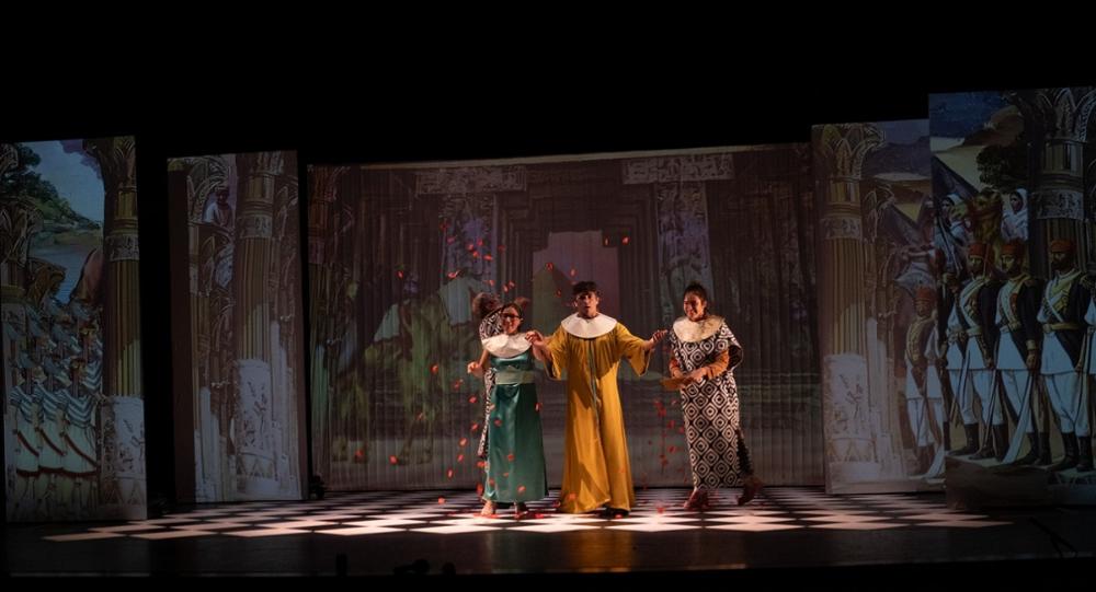 Escena teatral con tres actores en escenario decorado.