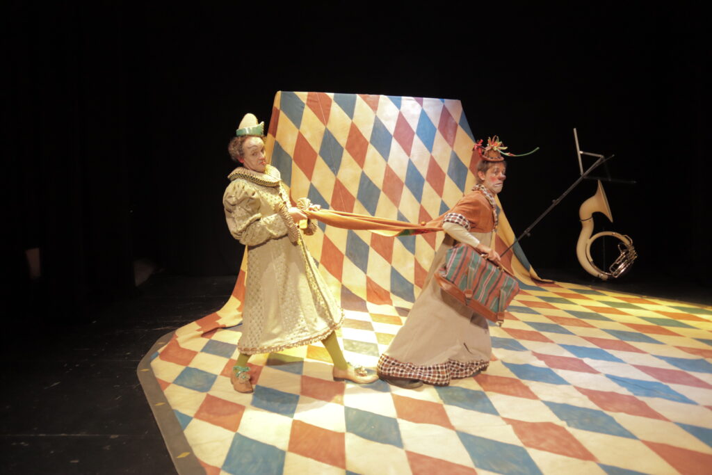 Payasos actuando en escenario colorido y teatral.
