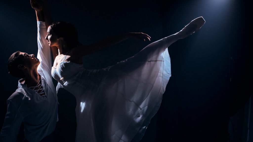 Pareja de bailarines haciendo ballet en el escenario.