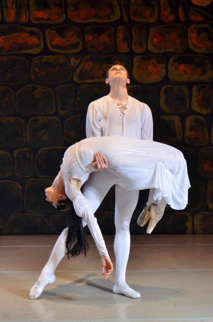 Bailarines en escena ejecutando postura elegante.