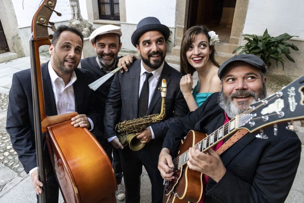 Grupo musical sonriente posando con instrumentos.