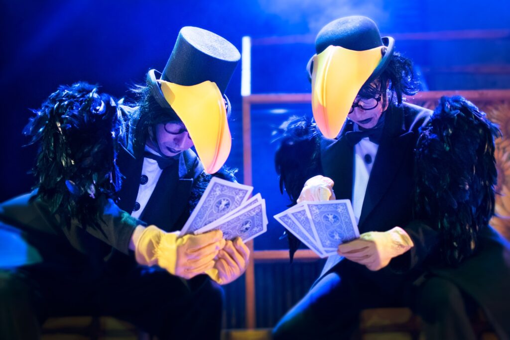 Dos personas disfrazadas de aves jugando al póker.