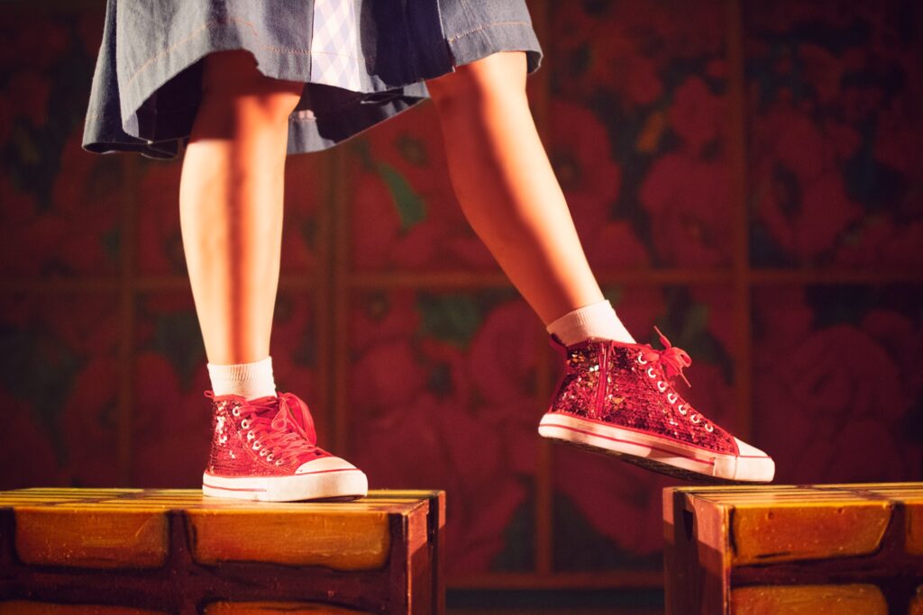 Piernas con zapatillas rojas brillantes sobre bloques.