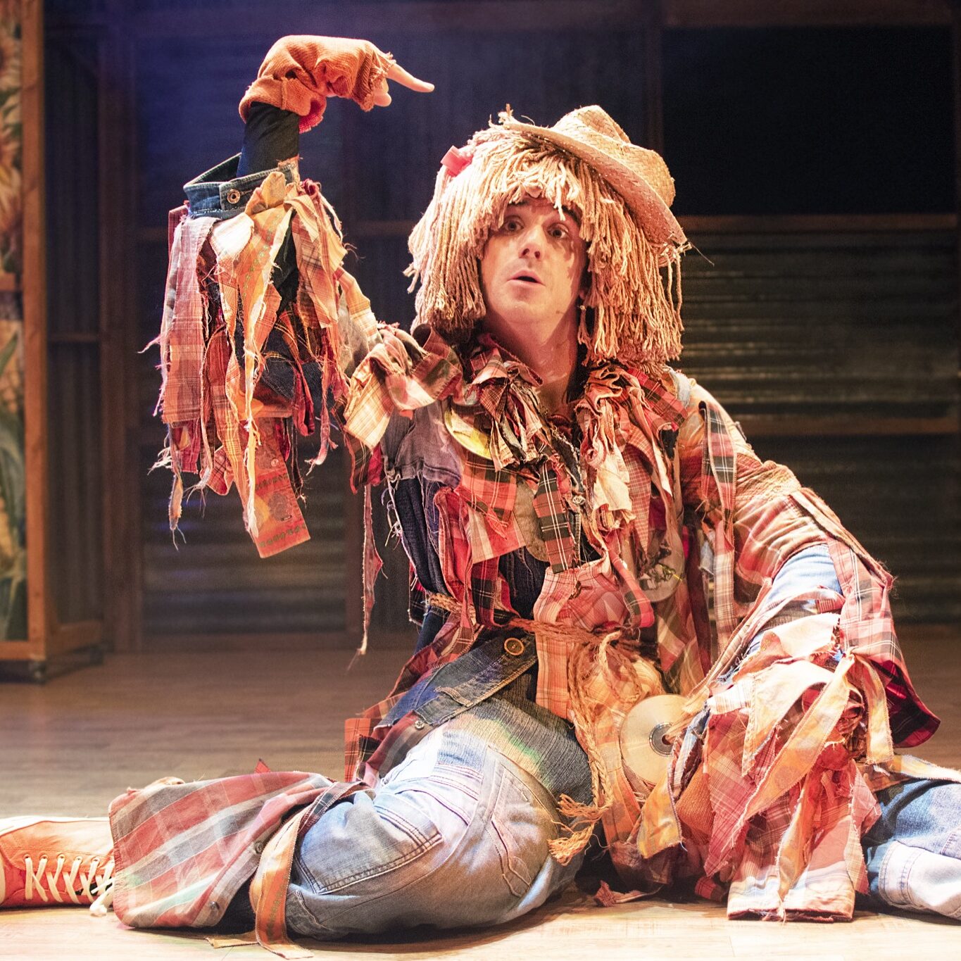 Actor disfrazado de espantapájaros en escenario teatral.