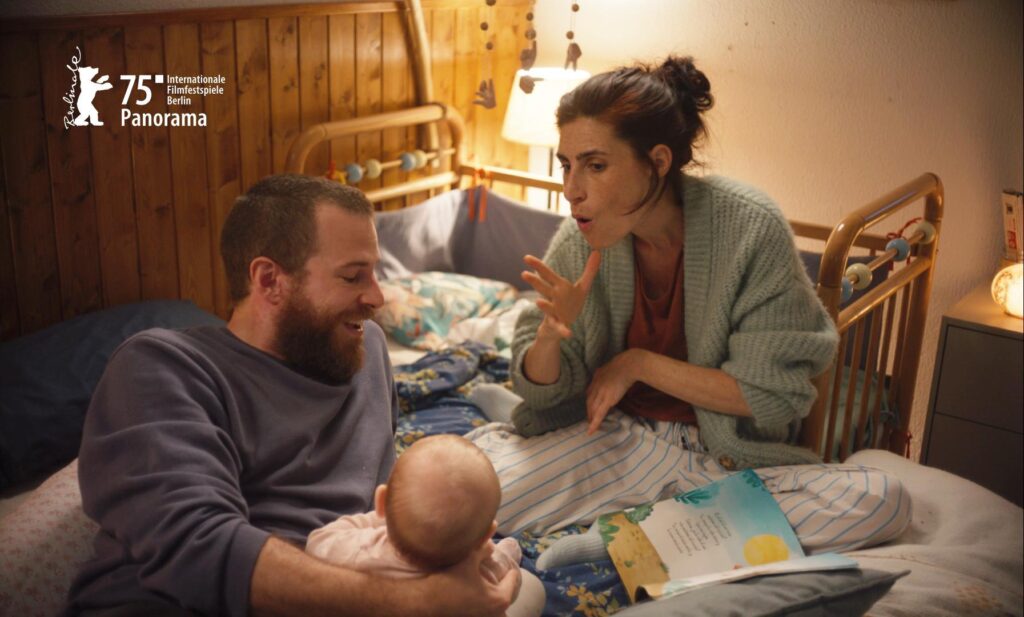 Familia leyendo a su bebé en la cama.