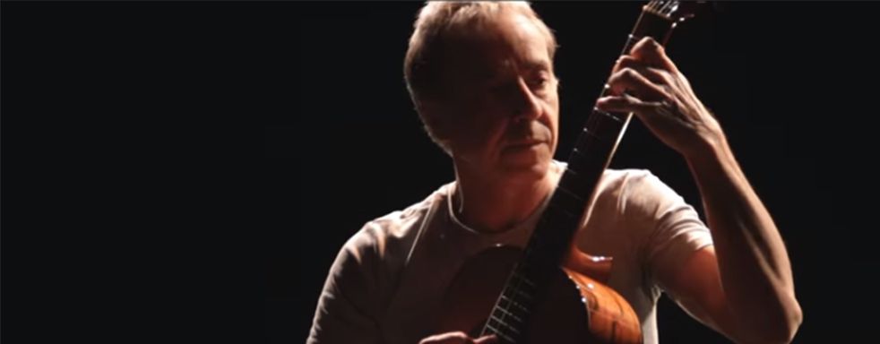 Persona tocando guitarra en iluminación oscura.