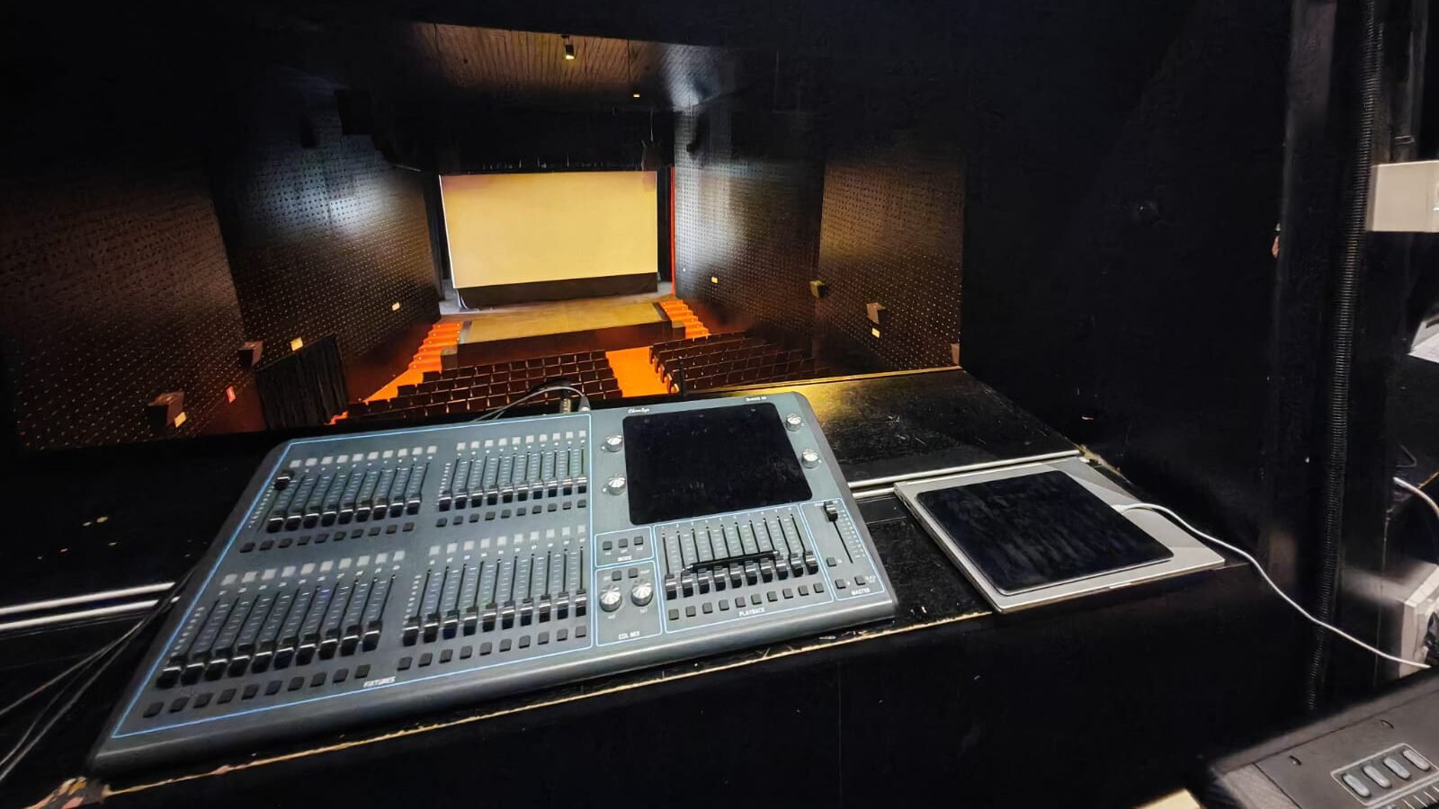 Cabina de control en auditorio con pantalla grande.