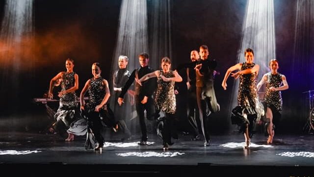 Grupo bailando flamenco en escenario iluminado.