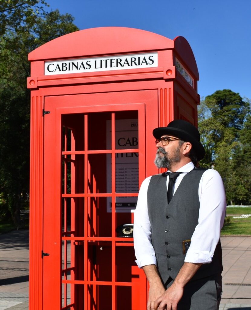 Cabina literaria roja, hombre elegante junto a ella.