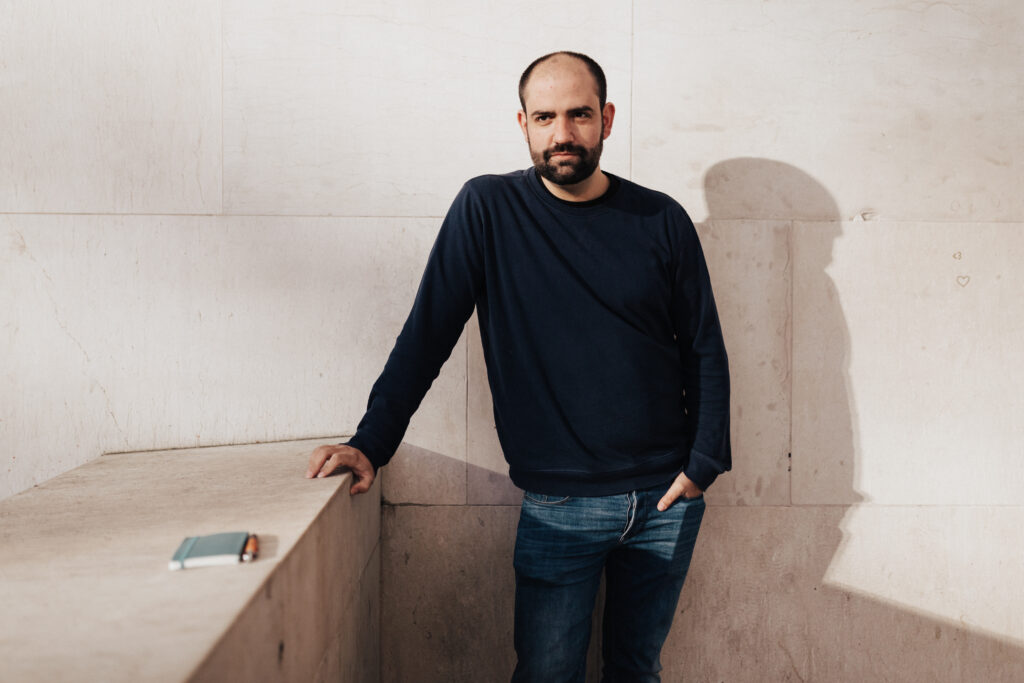 Hombre apoyado en pared de piedra beige