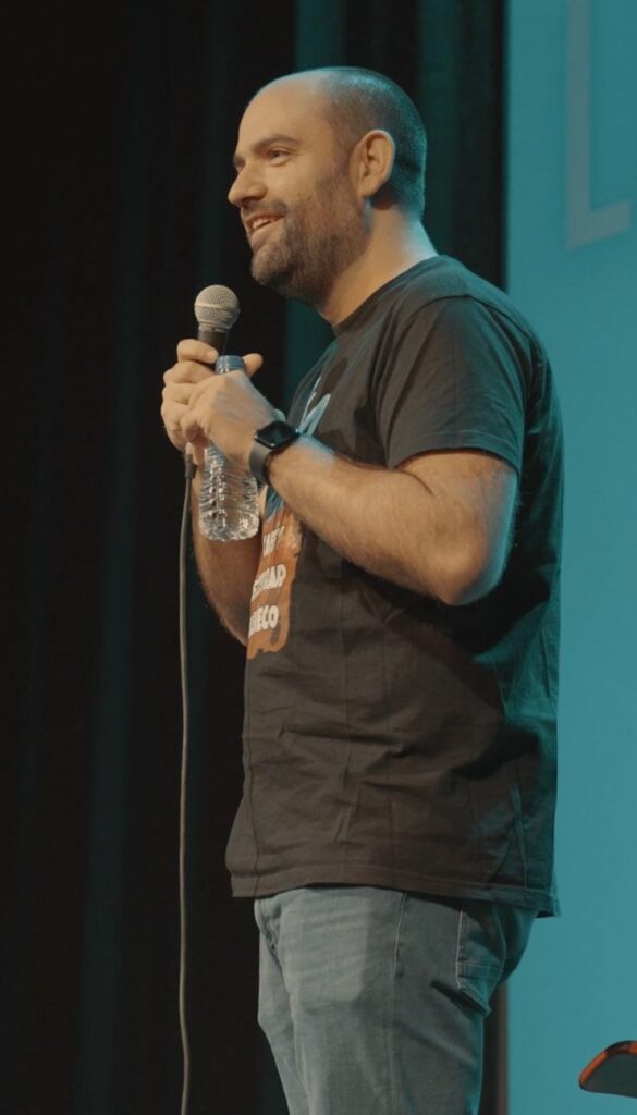 Hombre actuando en comedia en vivo con micrófono.