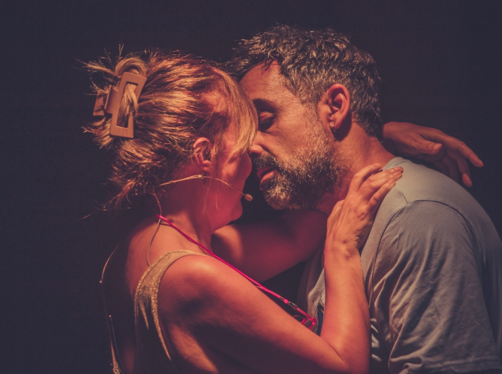 Pareja abrazándose con micrófonos, escena íntima.