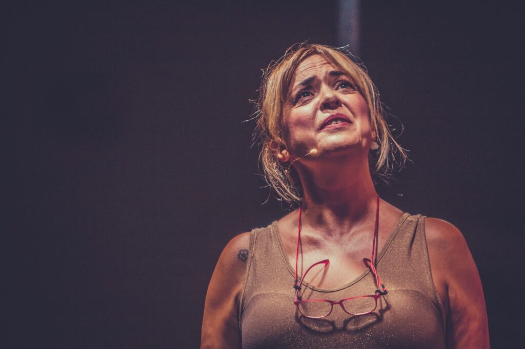 Mujer actriz en escenario emocionada.