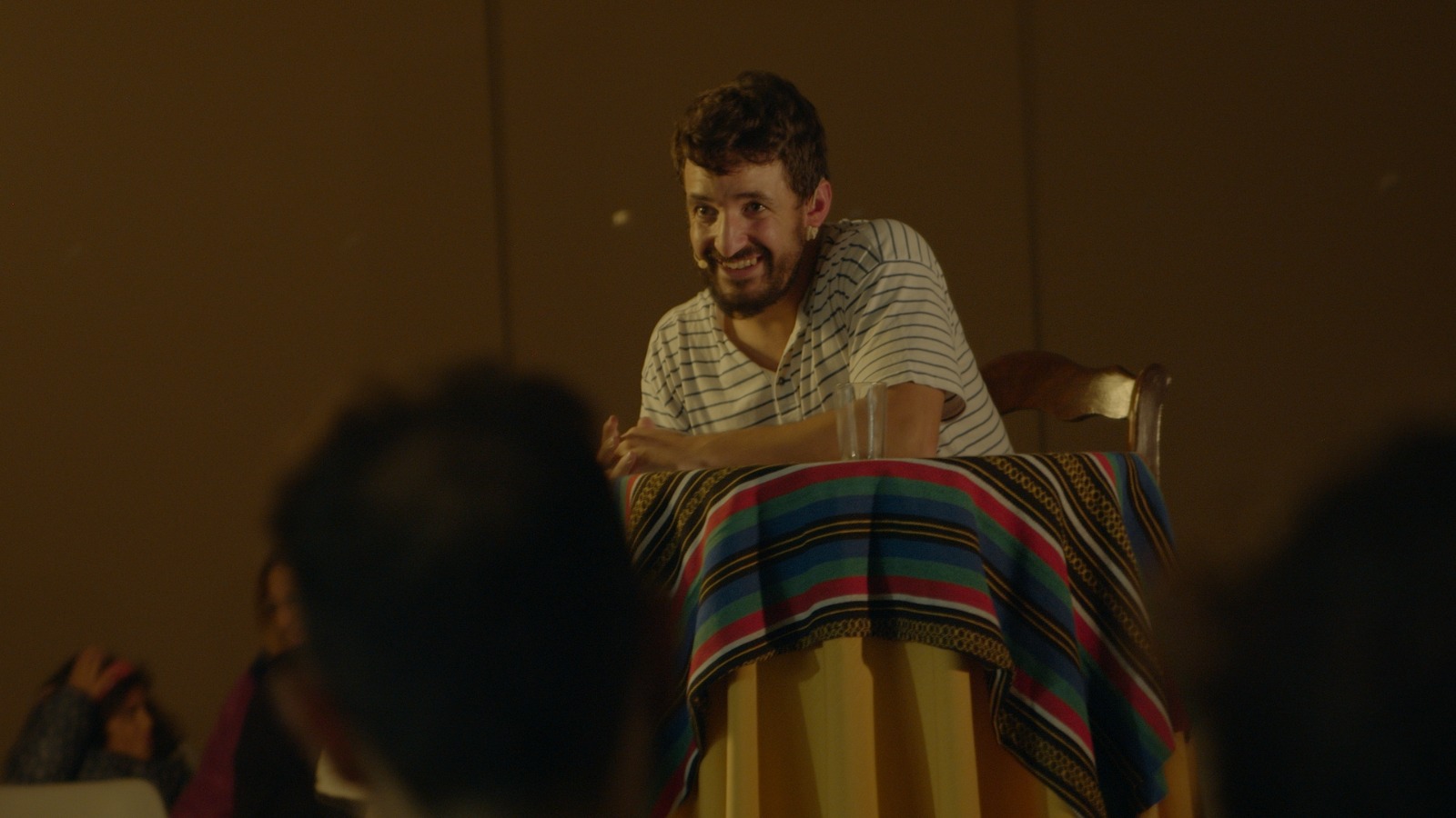 Hombre sonriente sentado en mesa decorada.