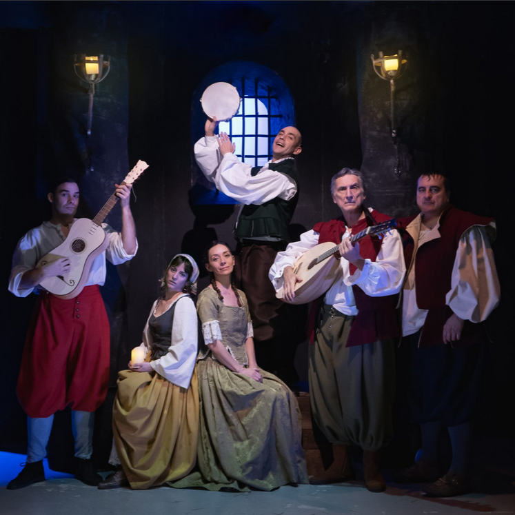 Actores con disfraces medievales tocando música en escena.