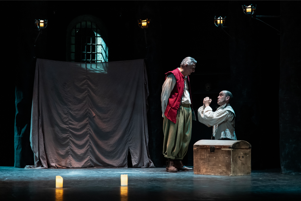 Escena teatral con dos actores y baúl