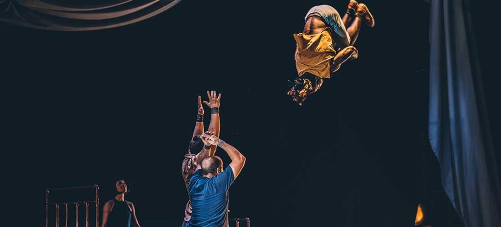 Acróbata realizando salto mortal en espectáculo circense.