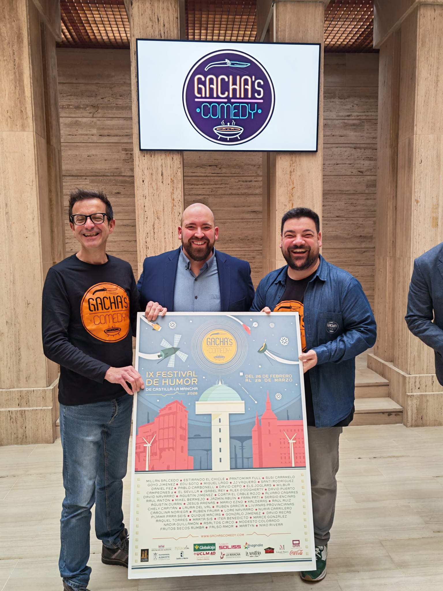 Tres hombres sostienen cartel de festival de comedia.