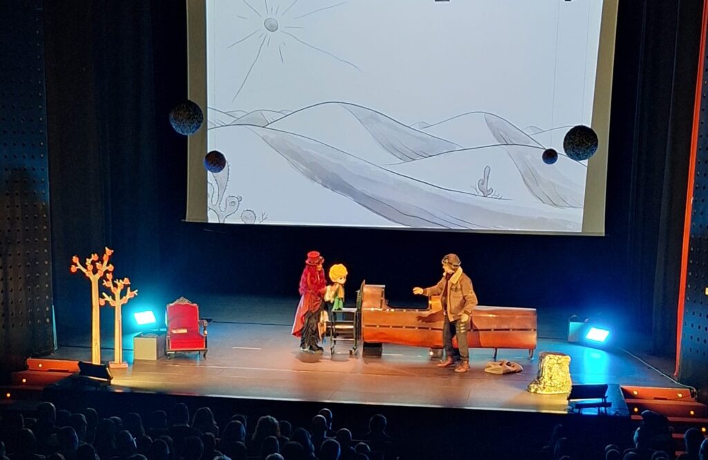 Actuación teatral con personajes y proyección de fondo