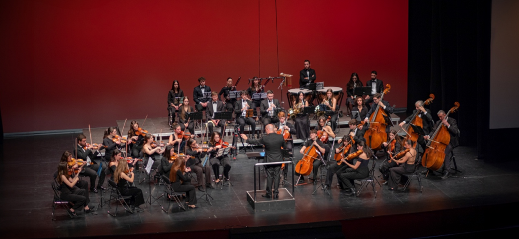 Orquesta sinfónica actuando en escenario con director