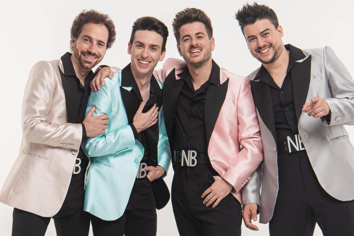 Cuatro hombres con chaquetas coloridas posando sonrientes