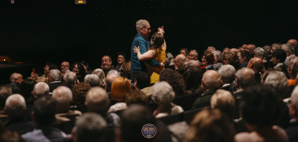 Pareja mayor bailando entre el público del teatro