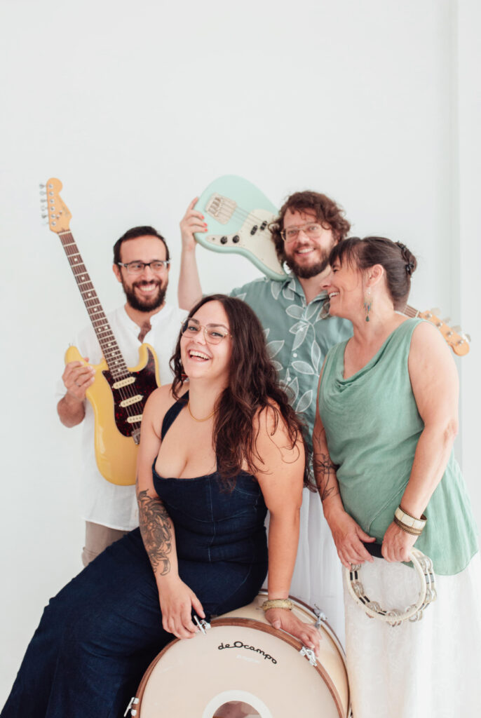 Cuatro músicos sonrientes con guitarras y tambor