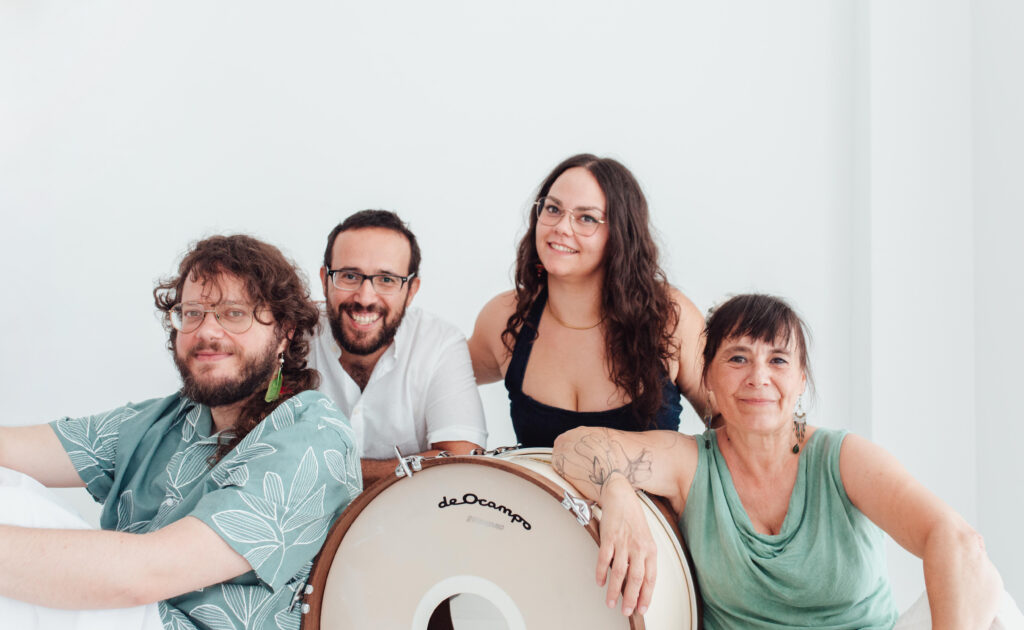 Cuatro músicos sonrientes con tambor grande