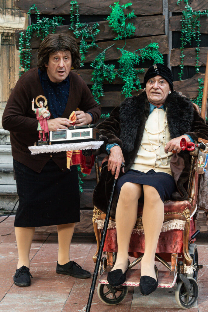 Dos personas caracterizadas como ancianas en escena cómica