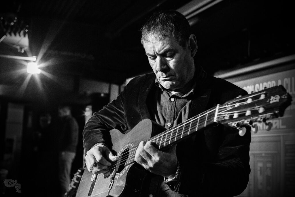 Guitarrista tocando en escenario con luz dramática