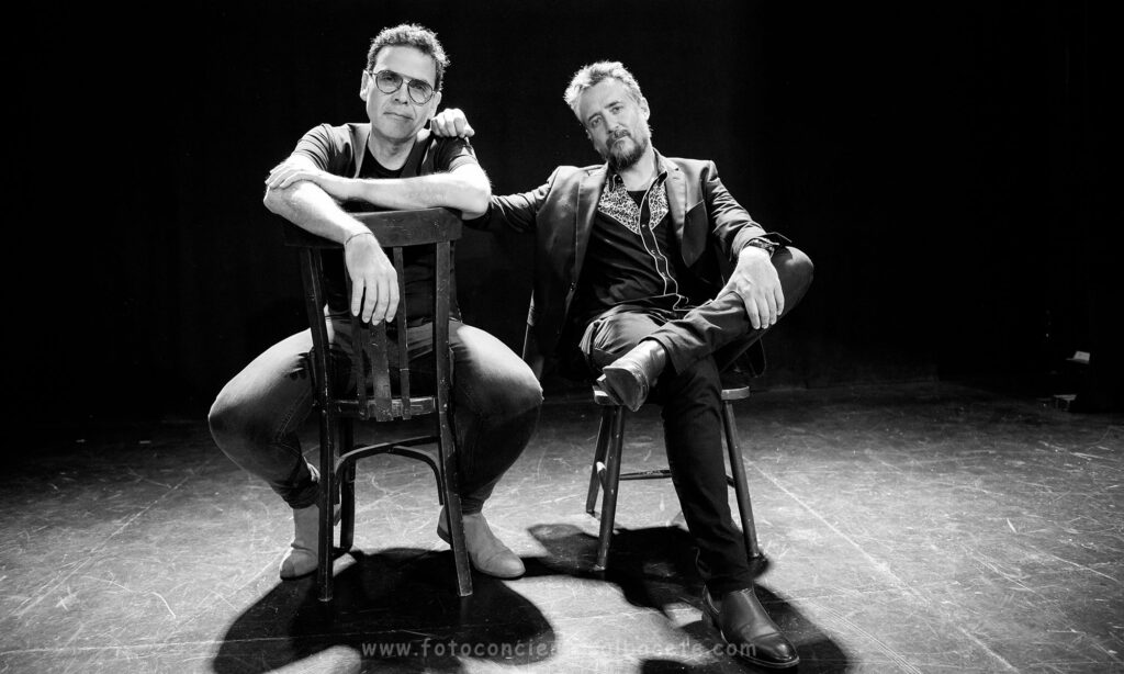 Dos hombres sentados en escenario en blanco y negro