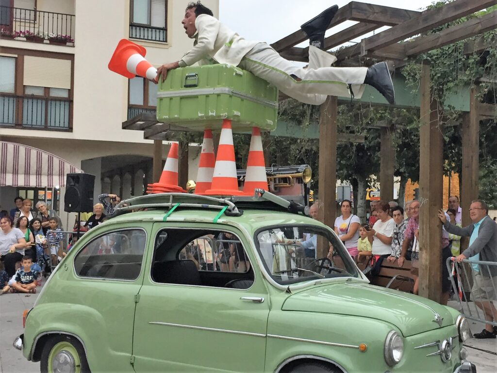 Artista sobre coche verde con conos de tráfico