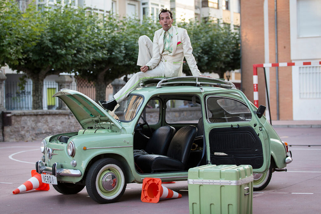 Hombre sobre coche vintage verde con capó abierto