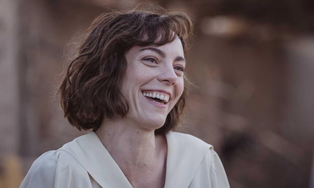 Mujer sonriente con pelo corto castaño al aire libre