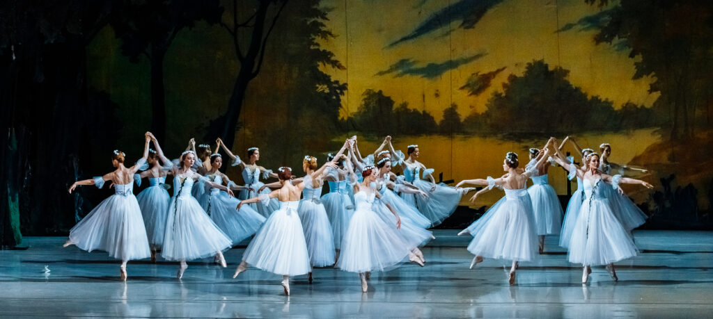 Cuerpo de ballet con tutús blancos sobre el escenario