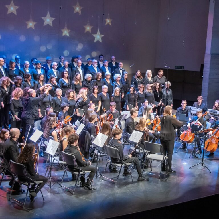 Coro y orquesta interpretan un concierto en el escenario
