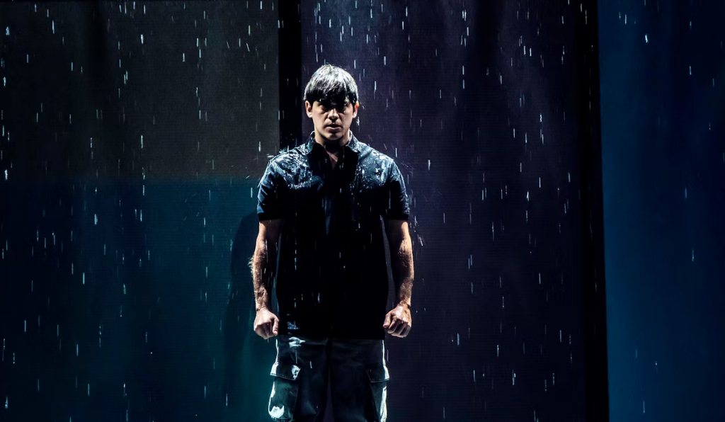 Hombre bajo la lluvia iluminado por focos azules