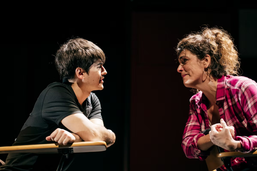 Dos personas conversan intensamente sentadas en un escenario