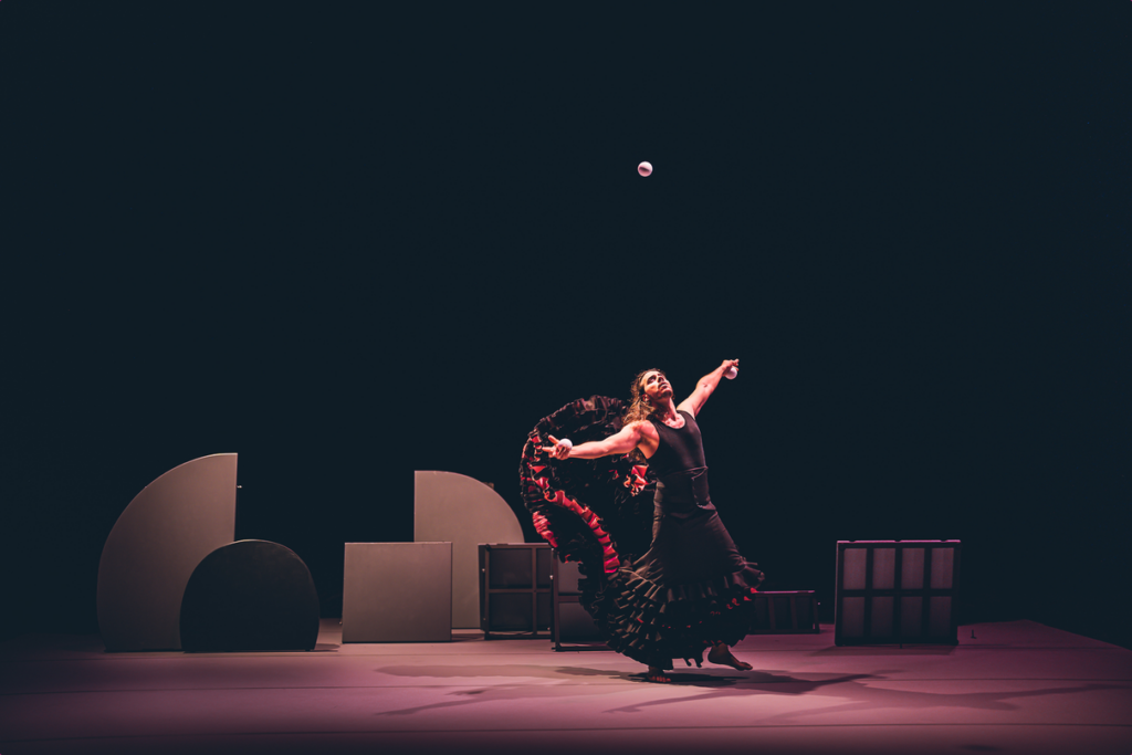 Bailaora de flamenco bajo una pelota en escenario oscuro