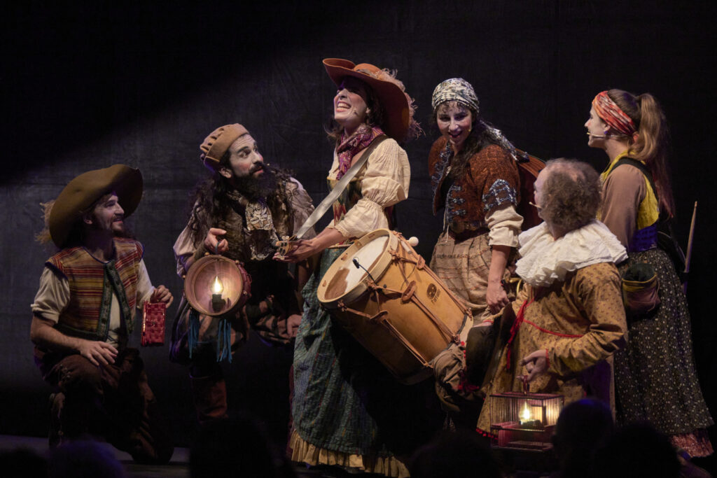 Grupo teatral con vestuario tradicional tocando instrumentos en escena