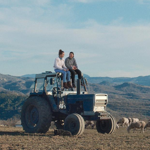 Dos personas sentadas sobre un tractor en el campo